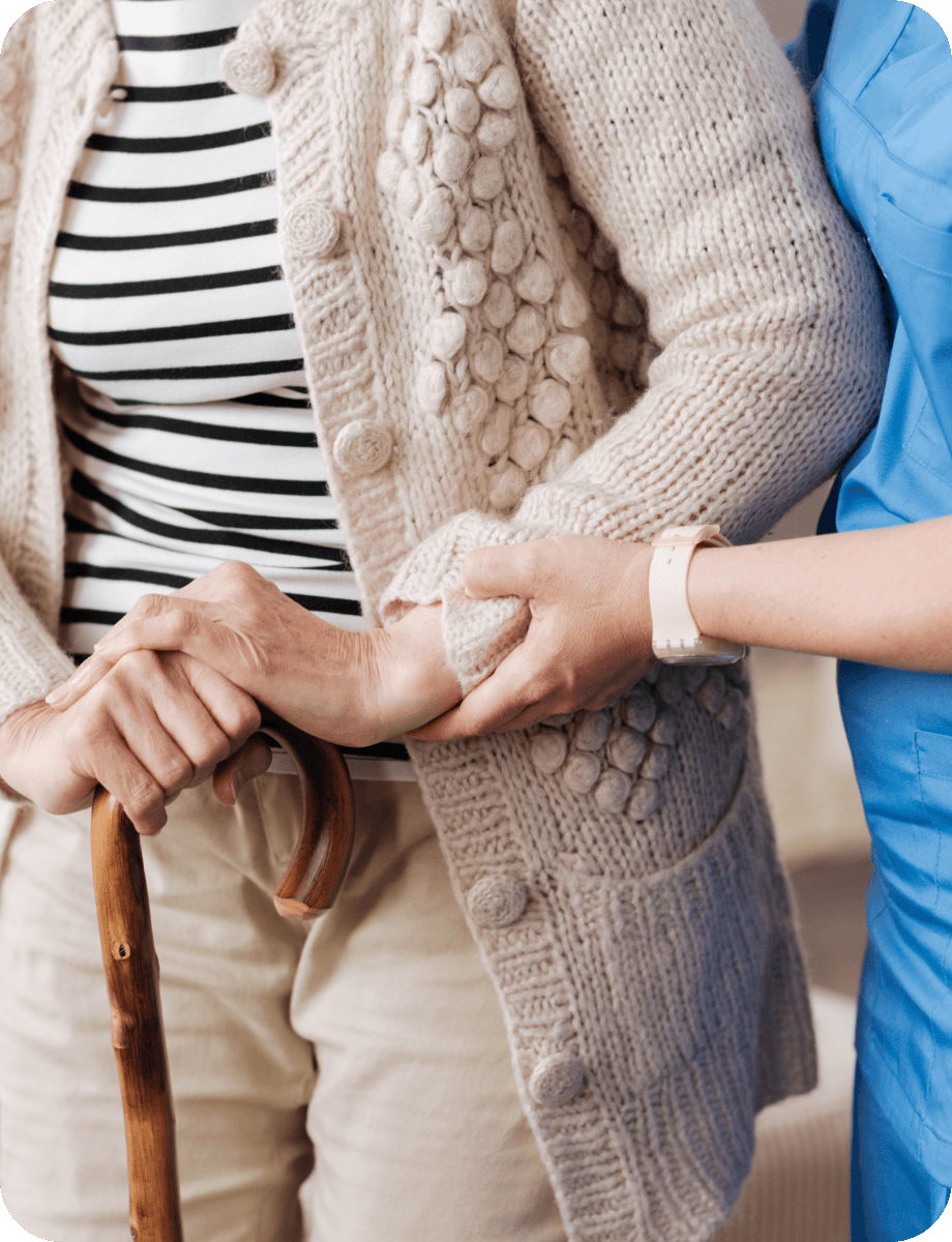Personne travailleur médical de l'association le Connétable à Dinan soutenant le bras d'une personne agée qui utilise une canne pour marcher.